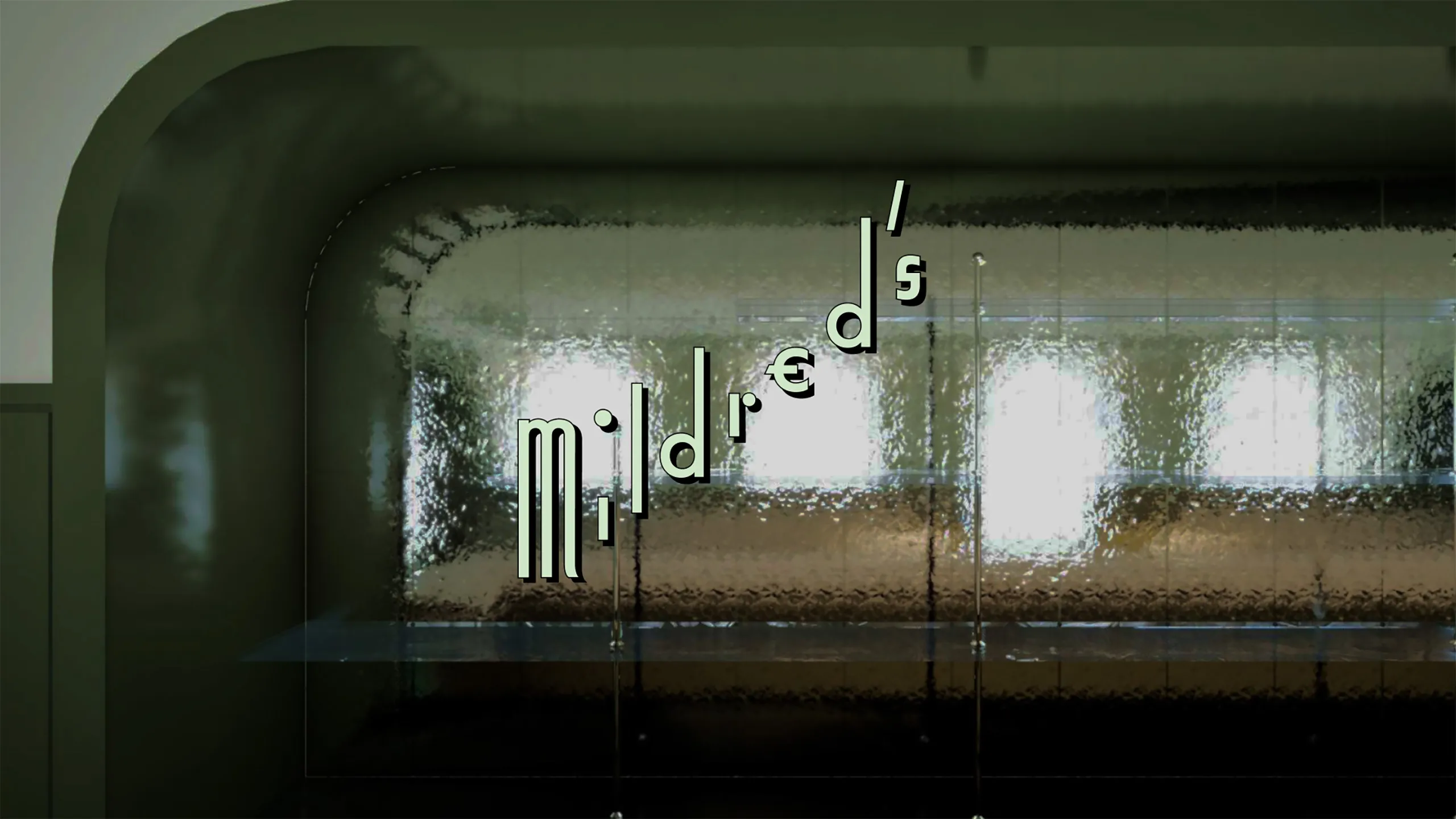 Curved glass wall with distorted reflections and the word 'Mildred's' displayed diagonally.