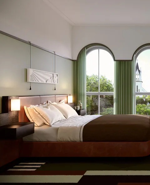Bed with white and brown bedding in room with green walls and large arched windows showing church tower.