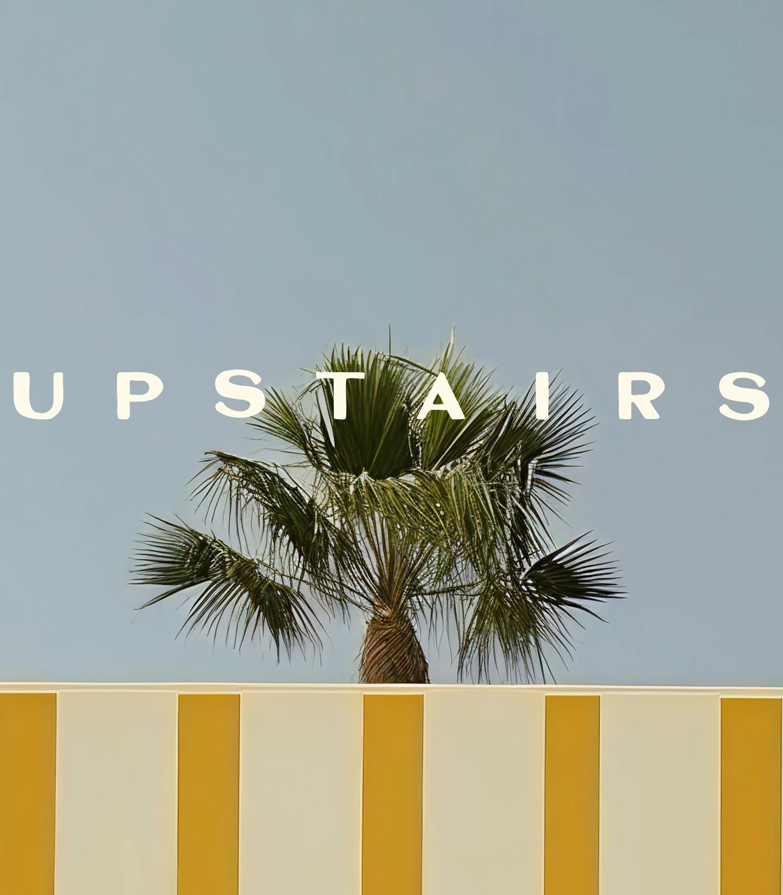 Palm tree behind a yellow and white striped wall under a clear blue sky with word 'UPSTAIRS' above.