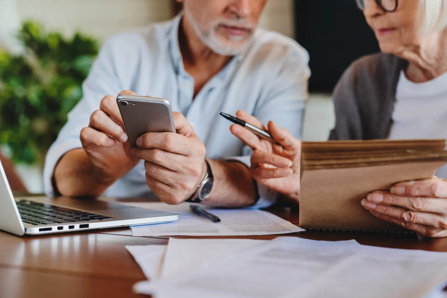 Two older adults sit at a table reviewing documents about tax and estate plans.