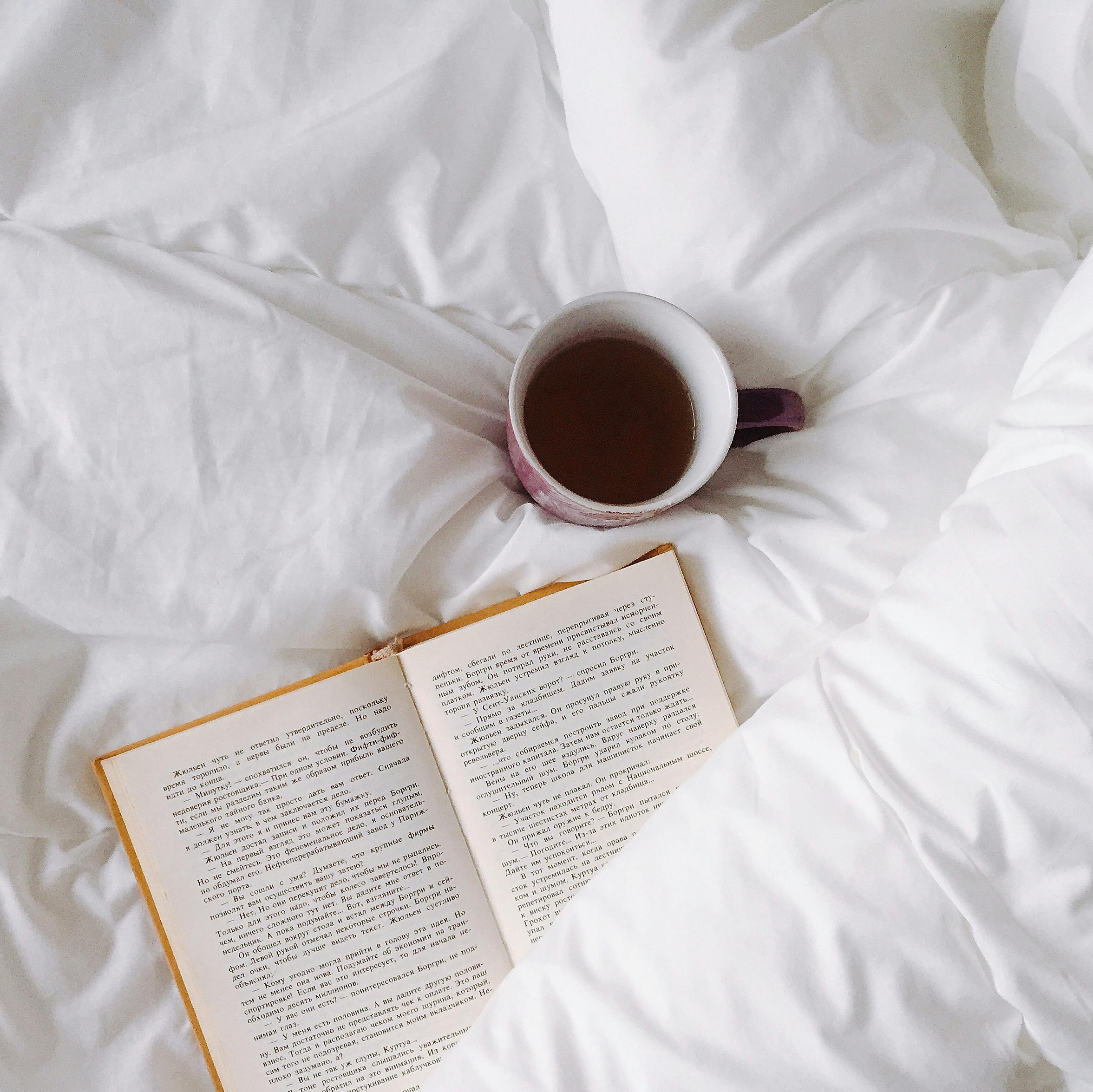 stock image of book on bed with coffee