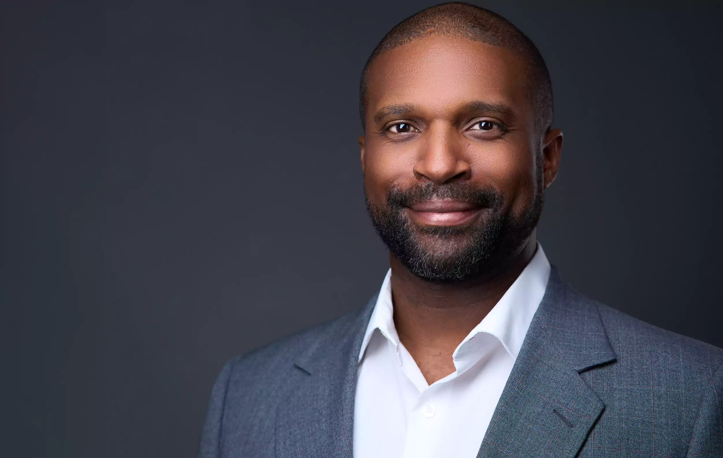 A man wearing a suit and tie smiles for the camera.