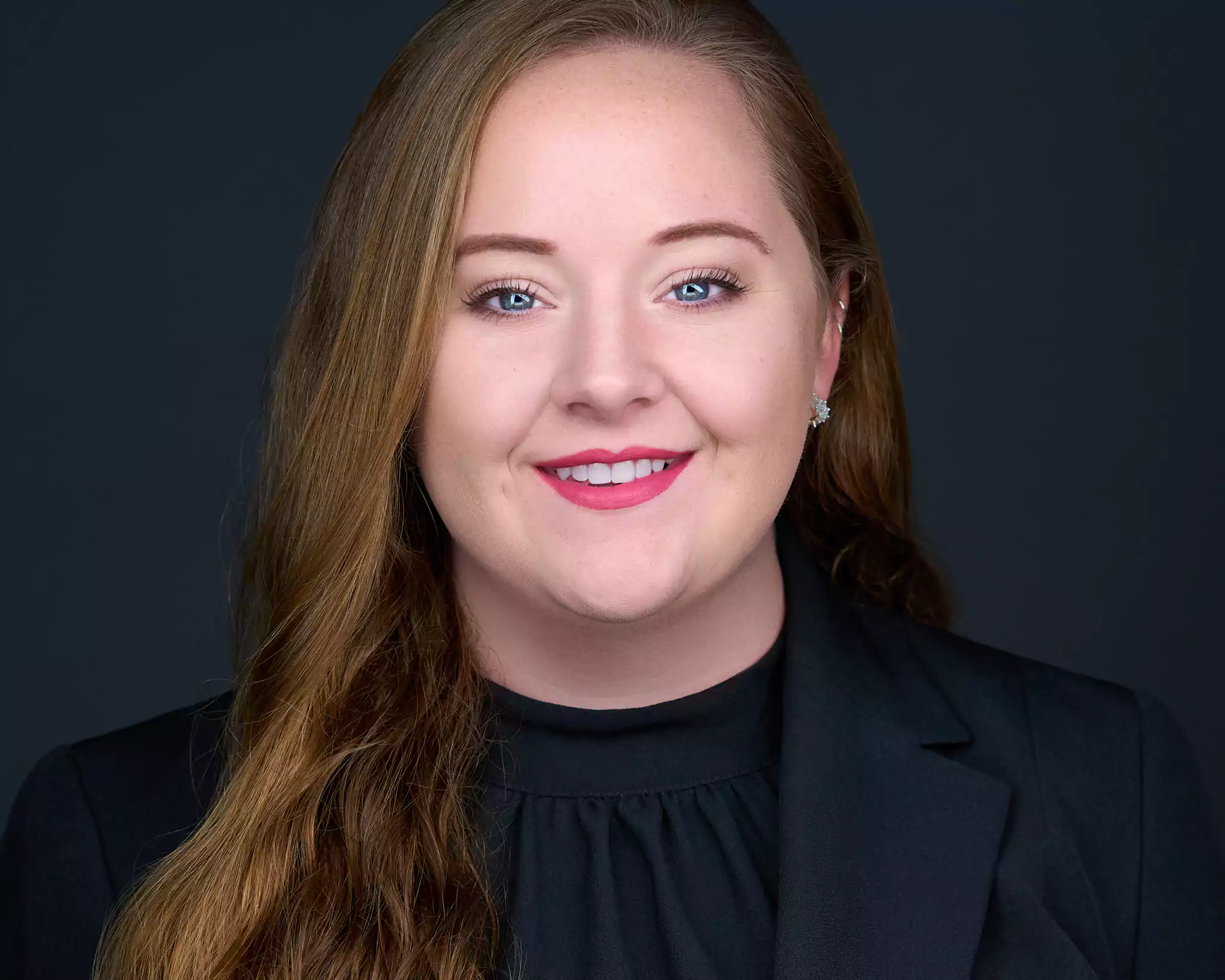 A woman with long hair and a black shirt smiling.