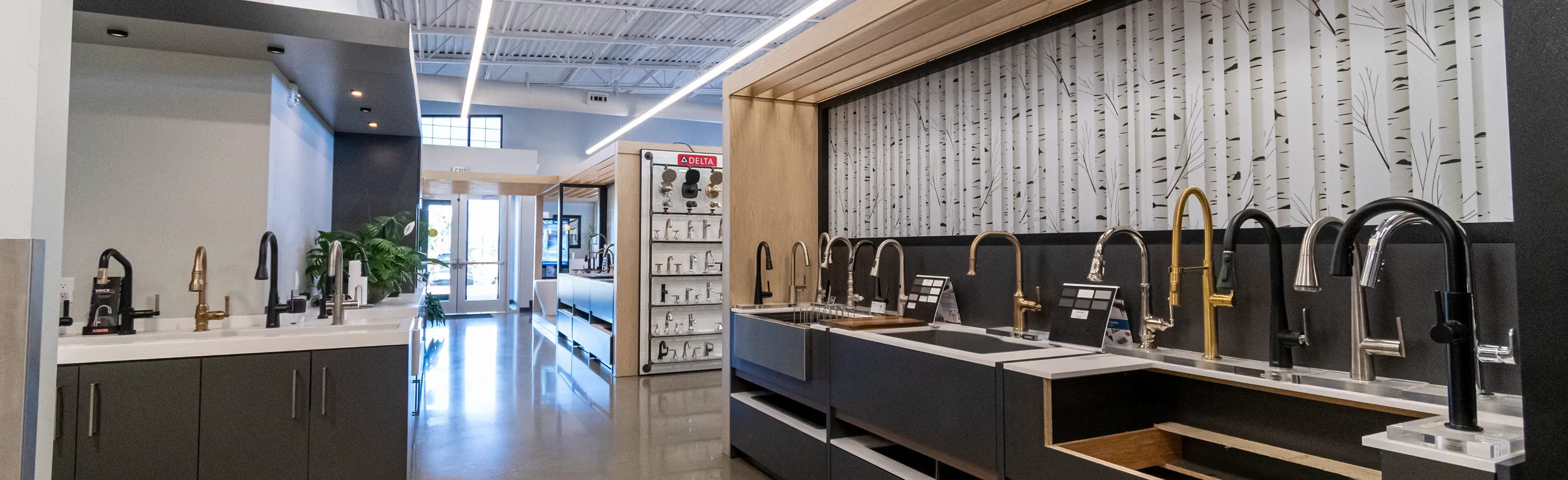 Row of contemporary faucet displays inside The Water Closet showroom with bright lighting and polished floors.