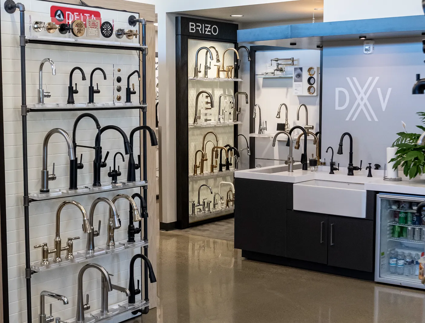 Showroom displaying various kitchen and bathroom faucets from brands Delta, Brizo, and DXV mounted on shelves and countertops.