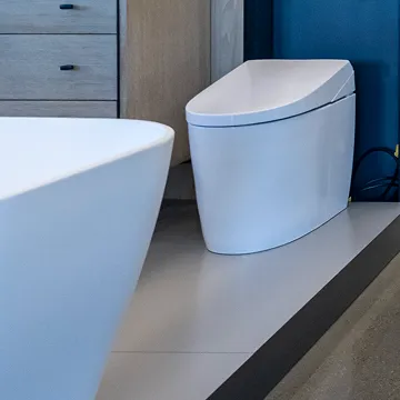 Sleek modern toilet displayed alongside bath fixtures inside The Water Closet showroom.