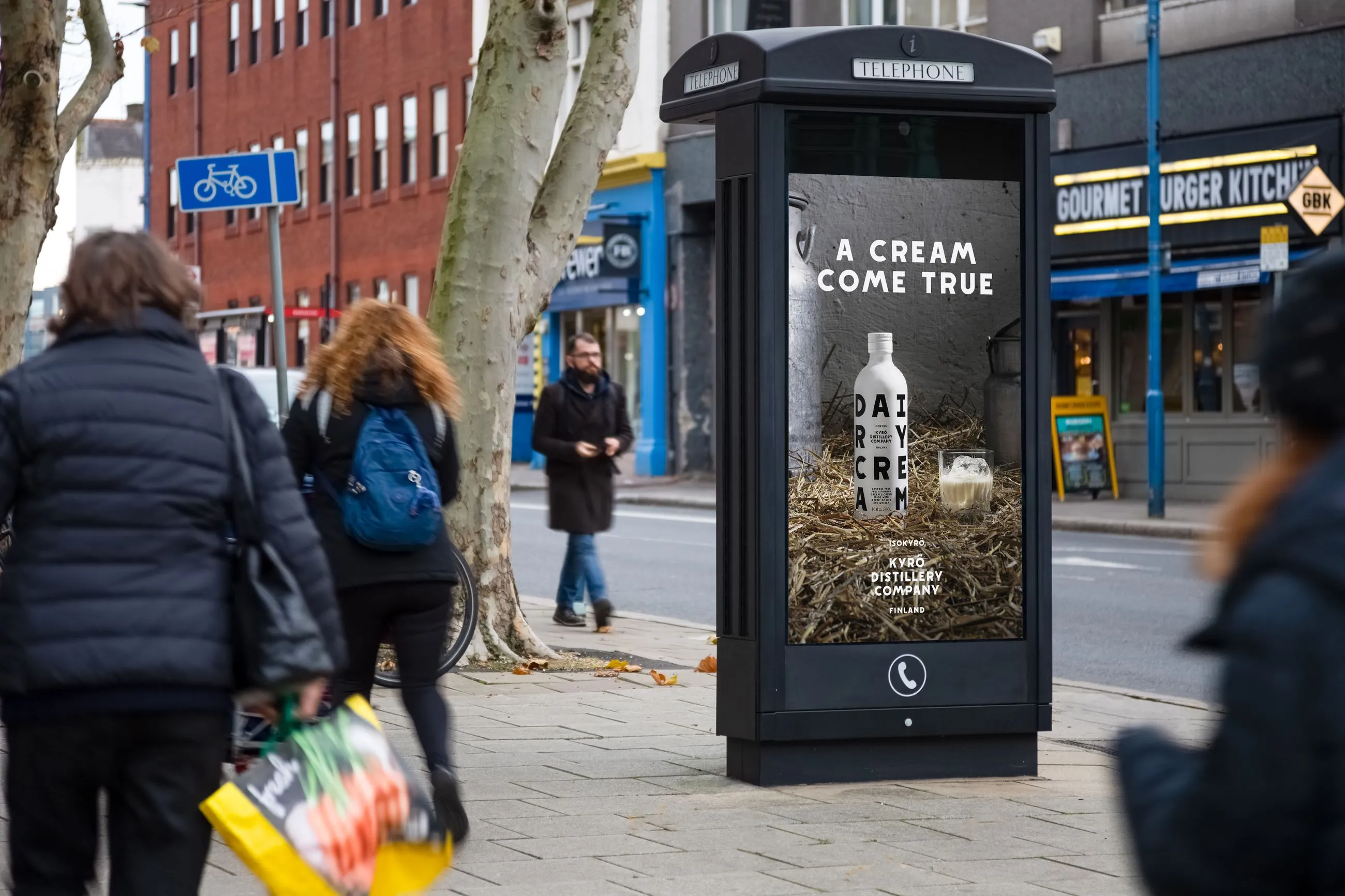 Digital phone box screen outside Gourmet Burger showing ad Kyro distillery
