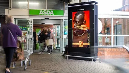 Bauer Media Outdoor digital advertising screen outside an ASDA supermarket displays a Toblerone ad featuring a model with the headline “Shine Bright Like a Truffle". 