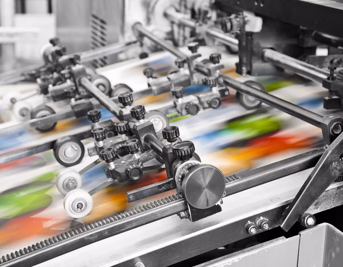 Drukmachine met kleurrijke bladen die snel door rollers bewegen.