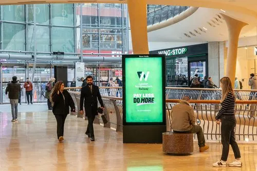 A railway ad campaign inside a shopping mall with shoppers walking by