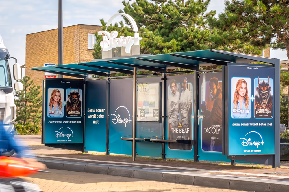 Bushalte gewrapt met Disney reclame en fietser die voorbij fietst
