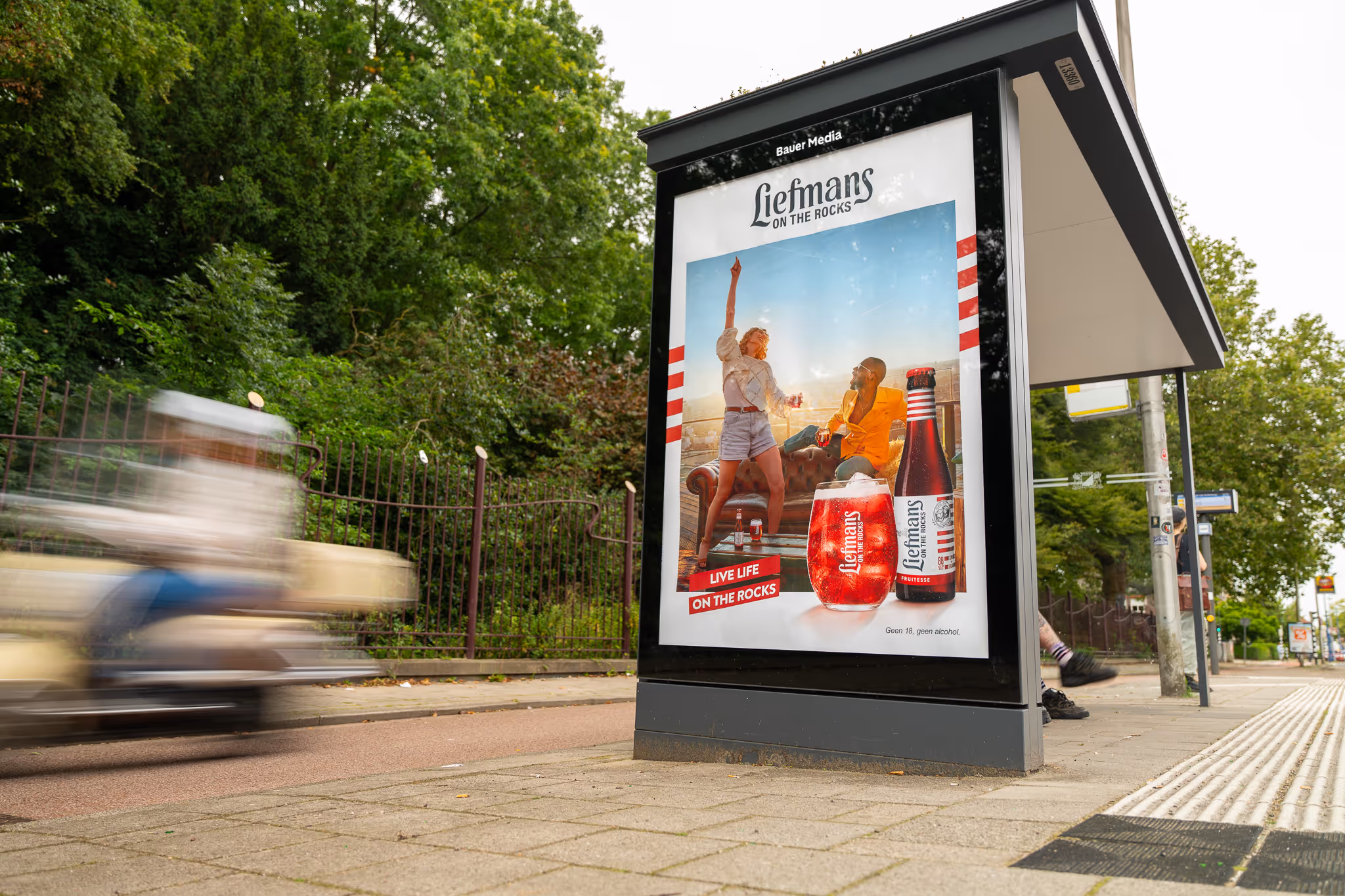 Bushalte met reclame en scooter rijdt voorbij