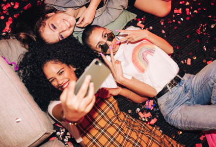 3 vrouwen liggen op grond en kijken naar smartphone