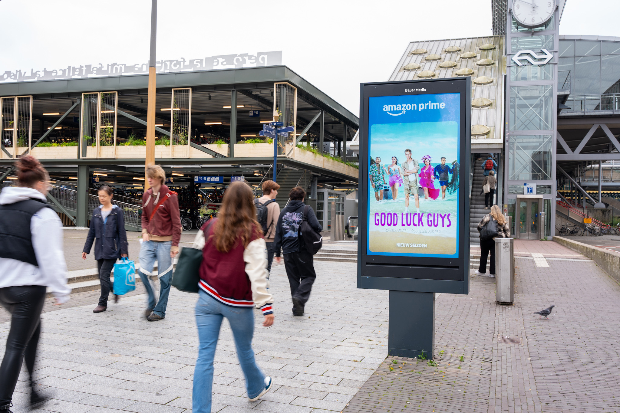 Digitaal scherm met Amazon Prime reclame voor Den Bosch station en voorbijgangers