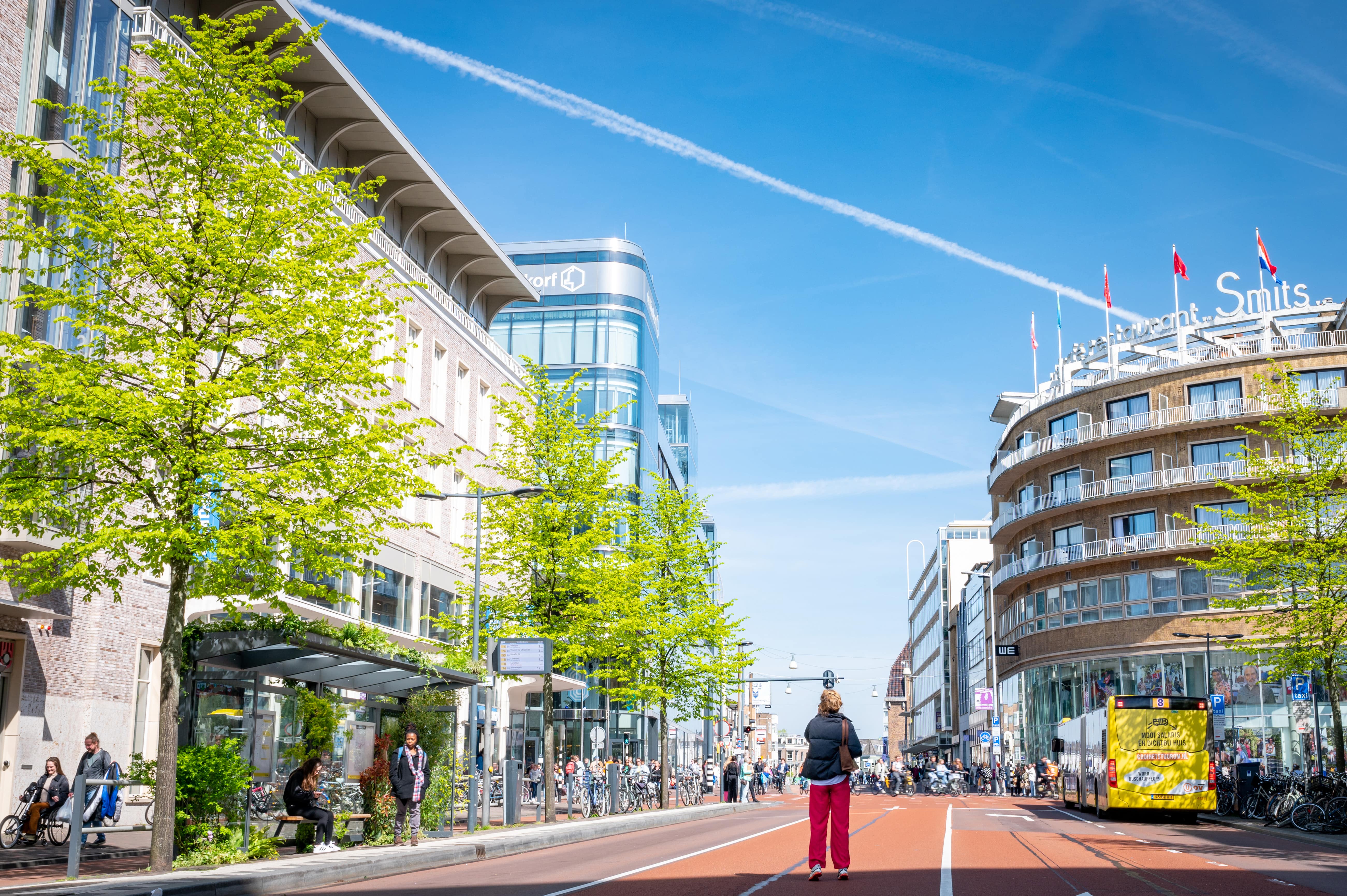 Bushalte met groene planten en voorbijgangers