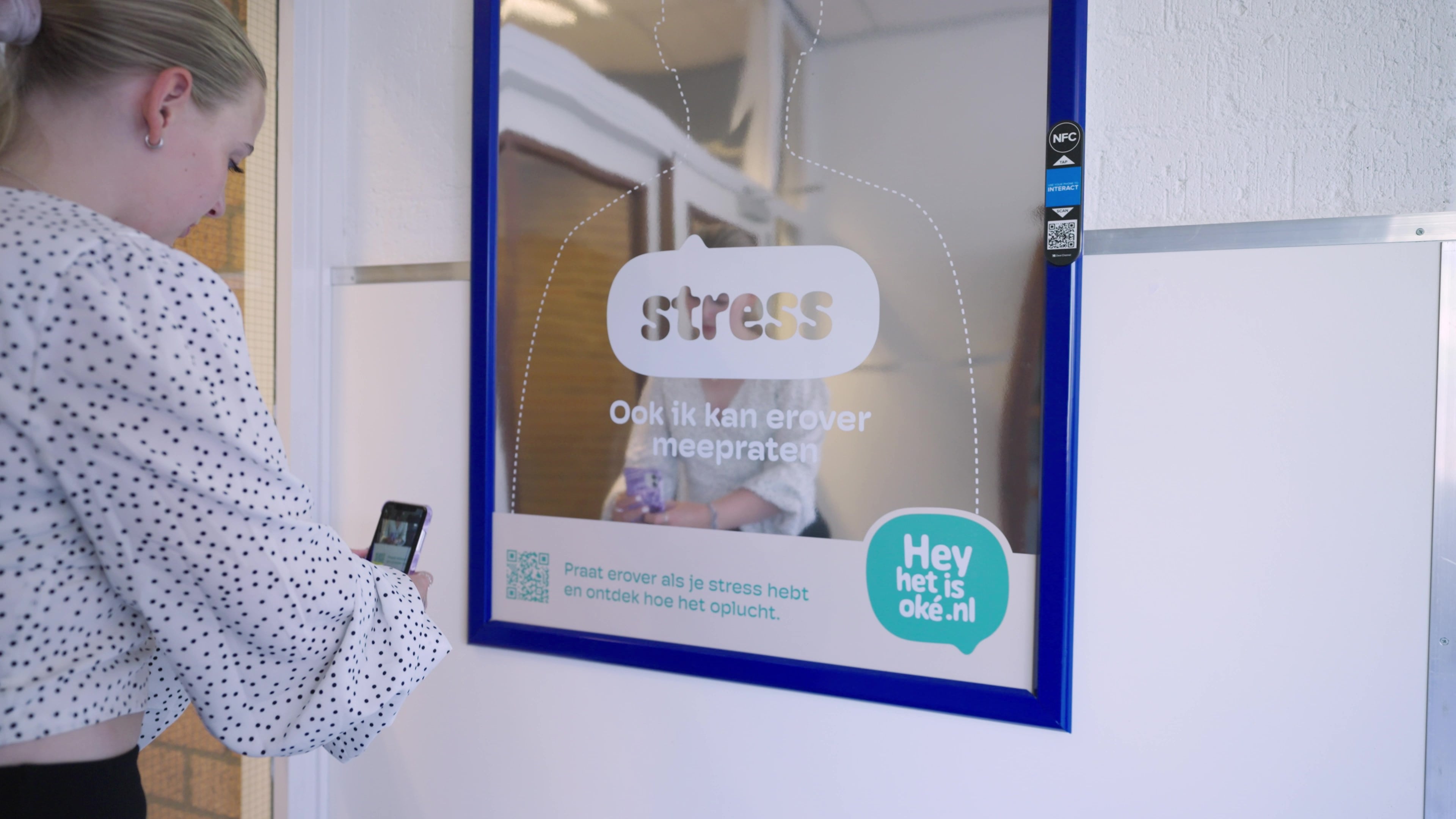 Vrouw scant QR-code op reclame met spiegeleffect en de tekst hey het is oke