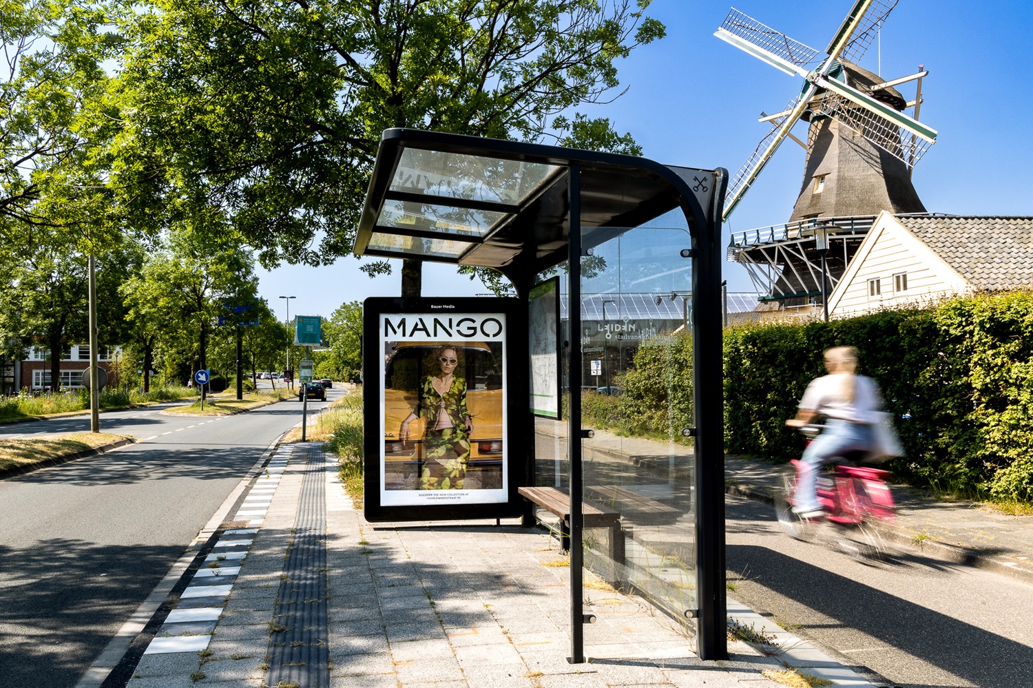 Bushalte in Leiden met Mango reclame en vrouw die voorbij fietst