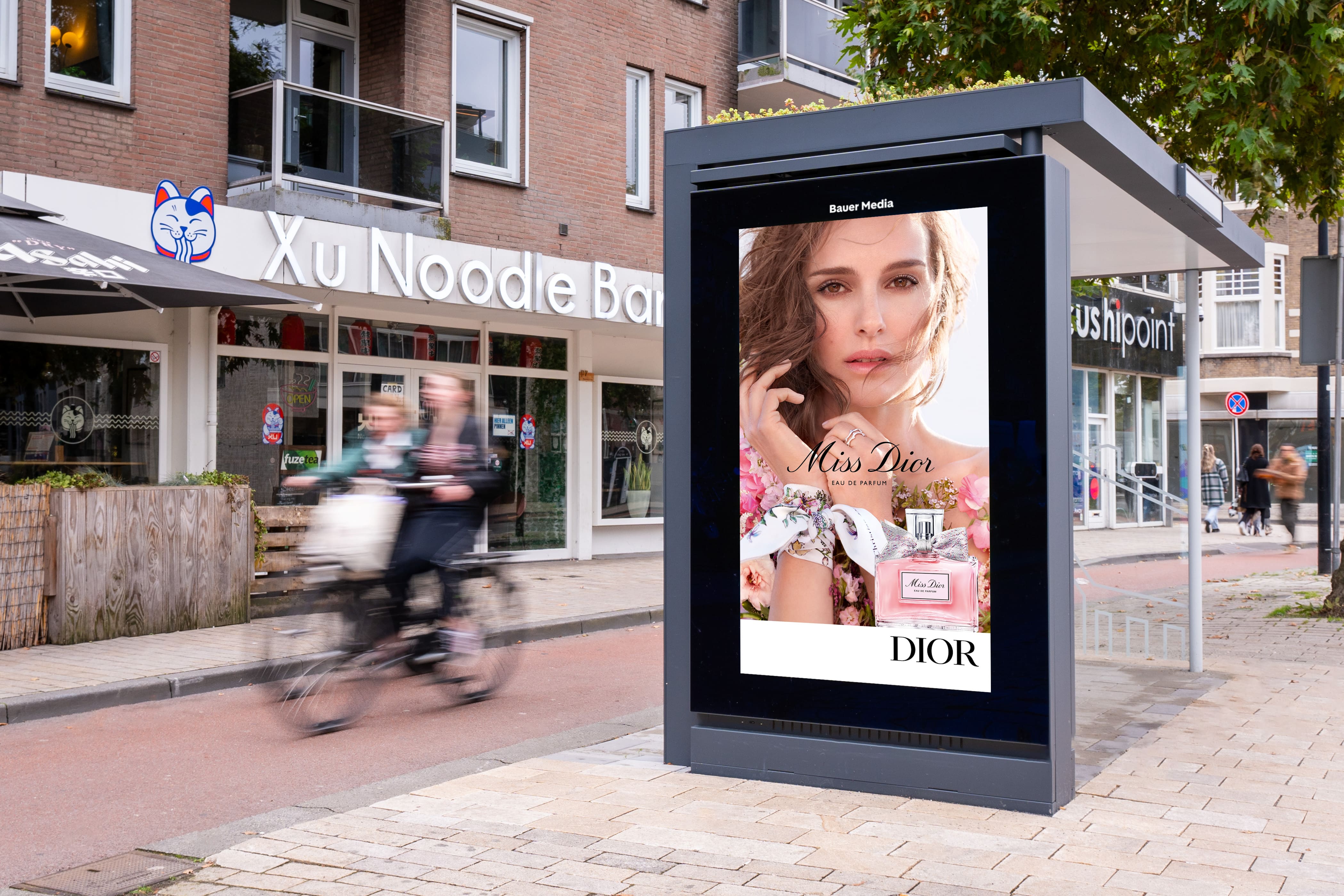 Bushalte met digitaal scherm en sedum dak met 2 fietsers op achtergrond