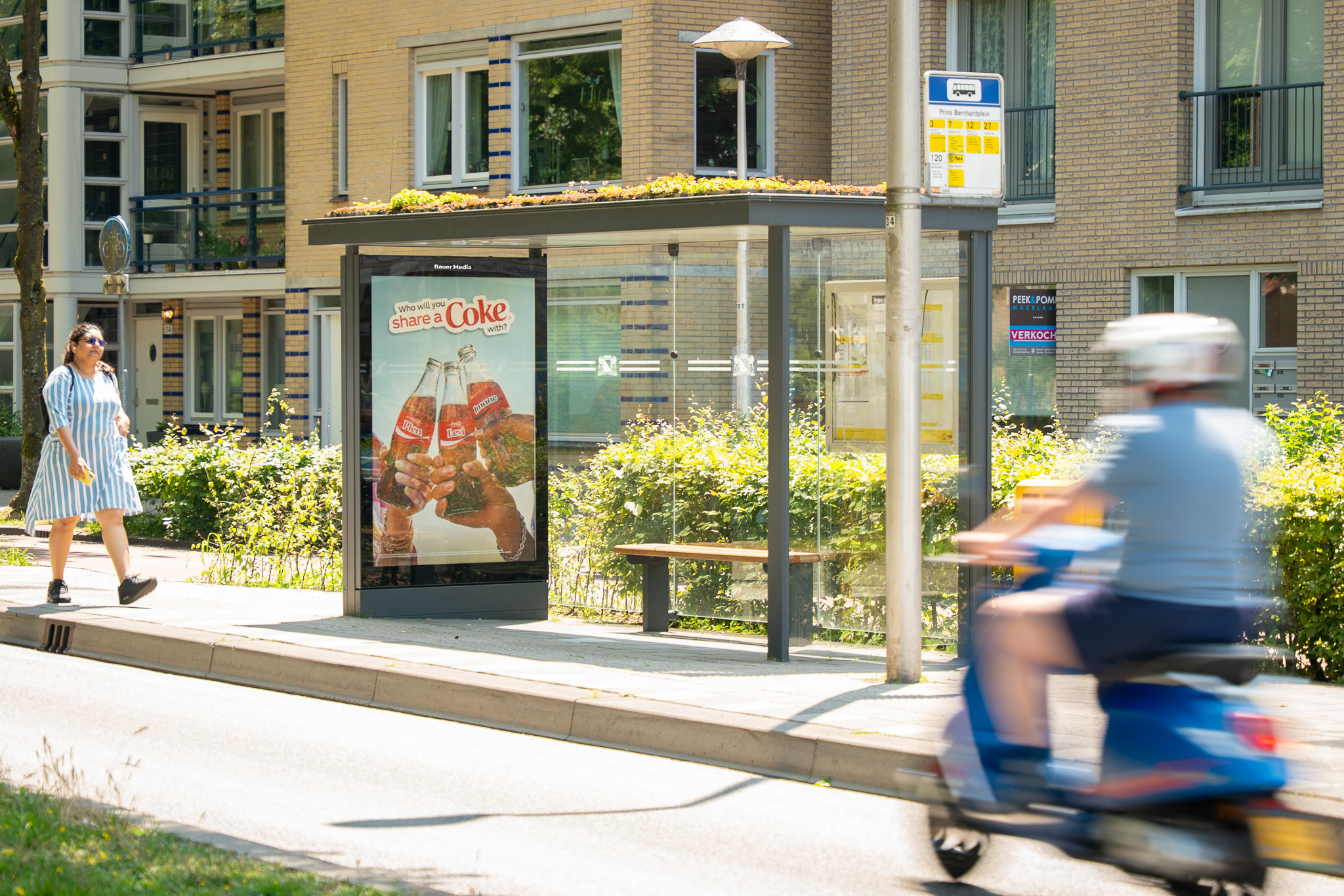 Bushalte met sedum dak en scooter die voorbij rijdt