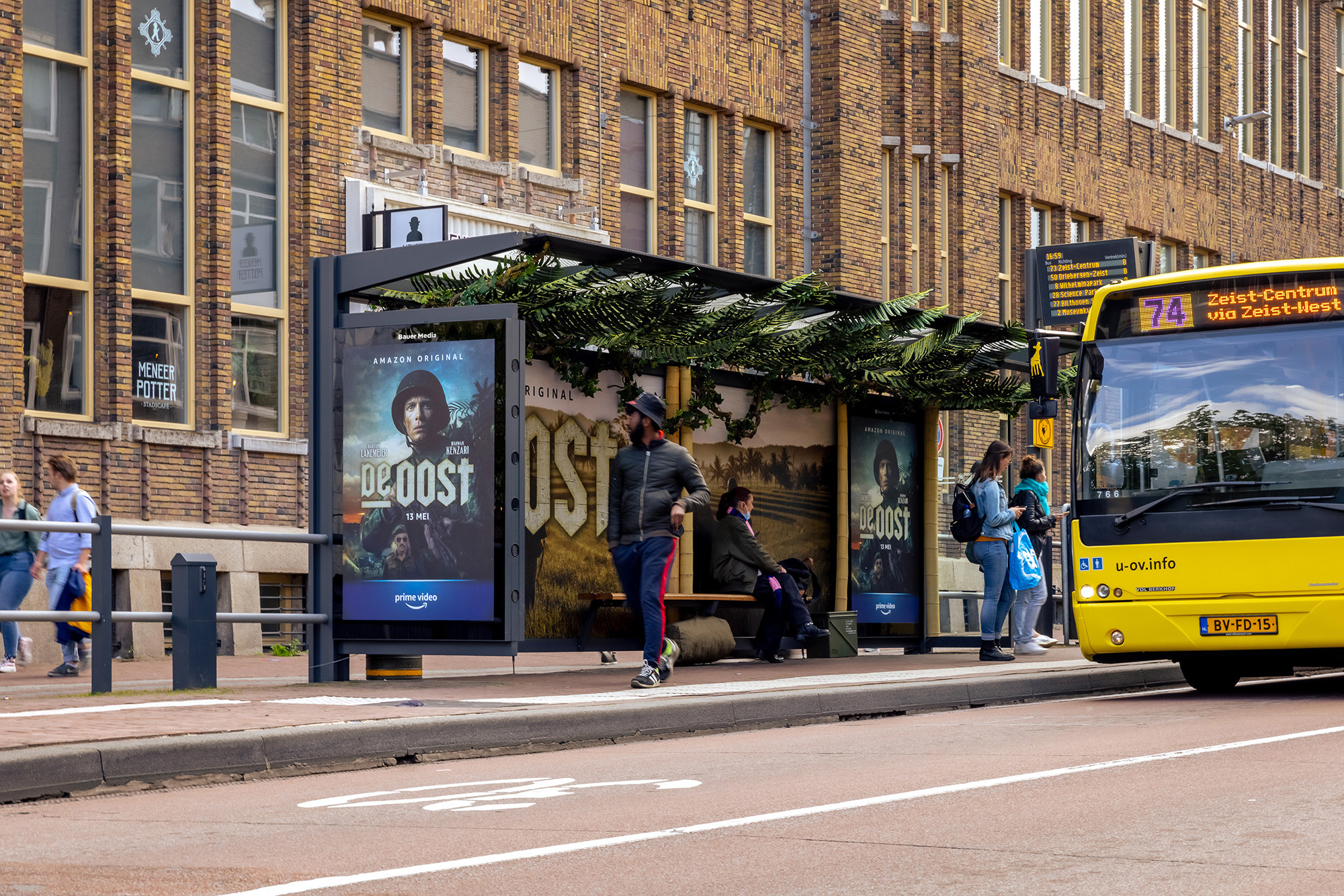 Bushalte met reclame van De Oost en bus rijdt voorbij