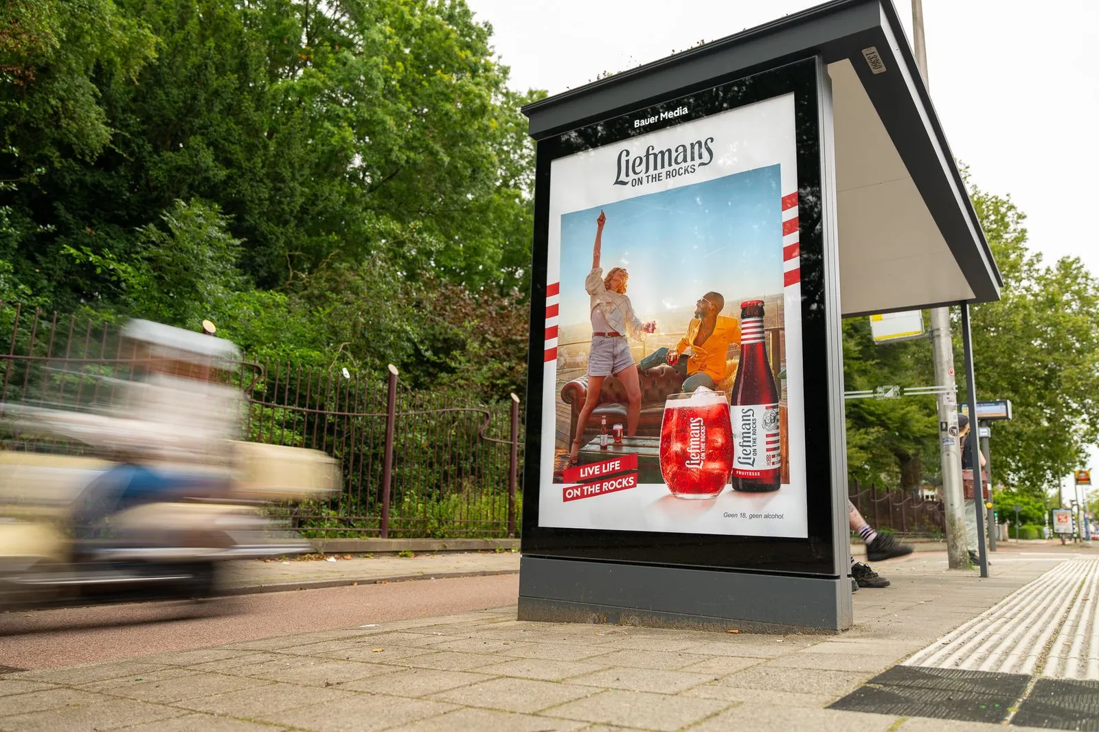 Bushalte met reclame en scooter rijdt voorbij