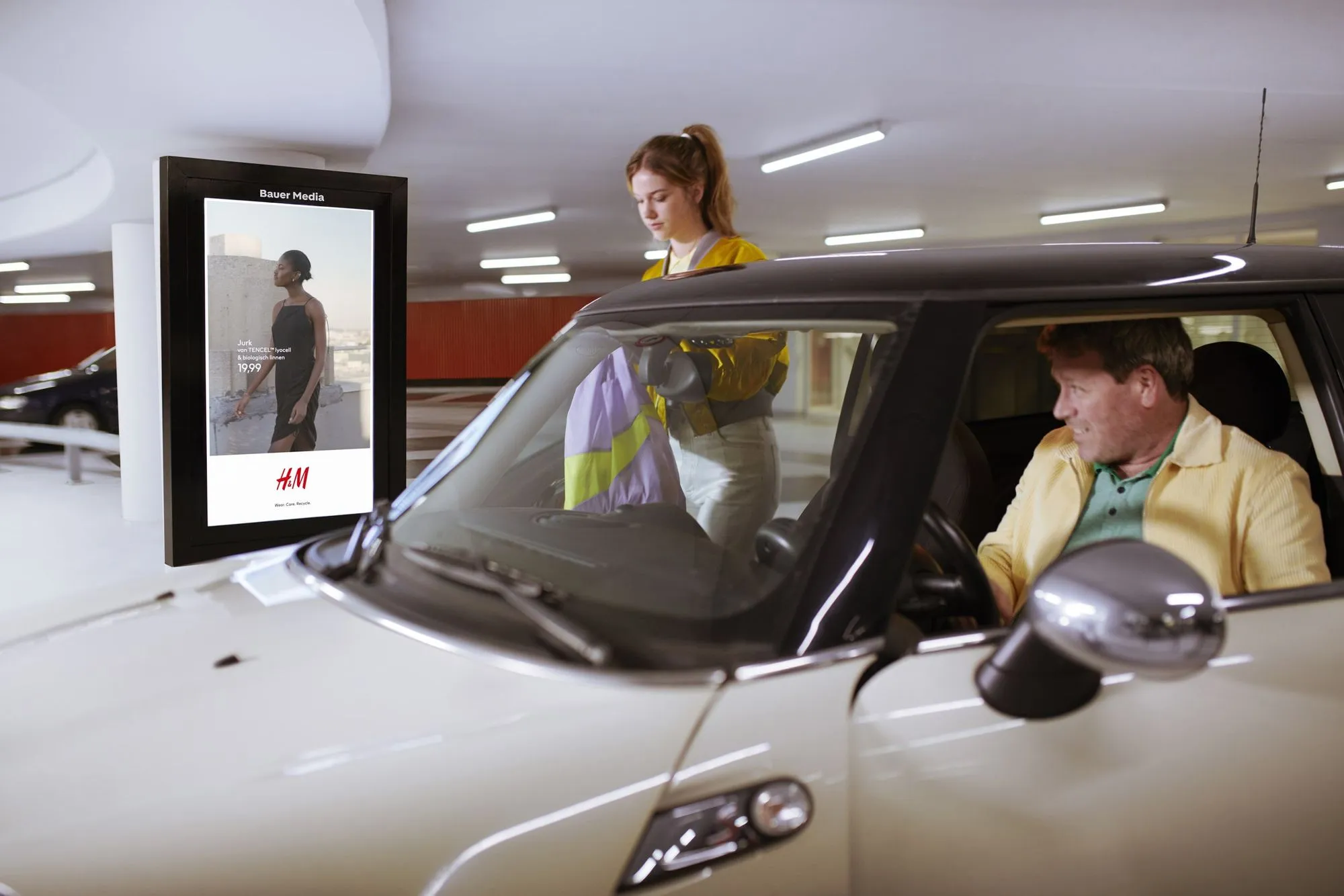 Meisje stapt uit auto en op achtergrond hangt een digitaal scherm met reclame