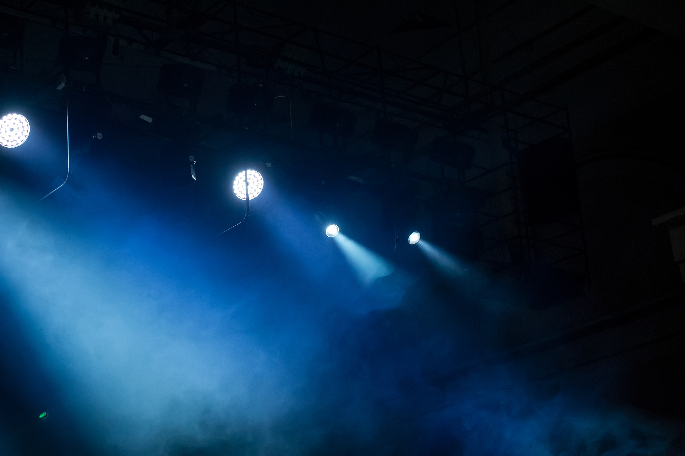 Stage spotlights cutting through haze on a dark production set