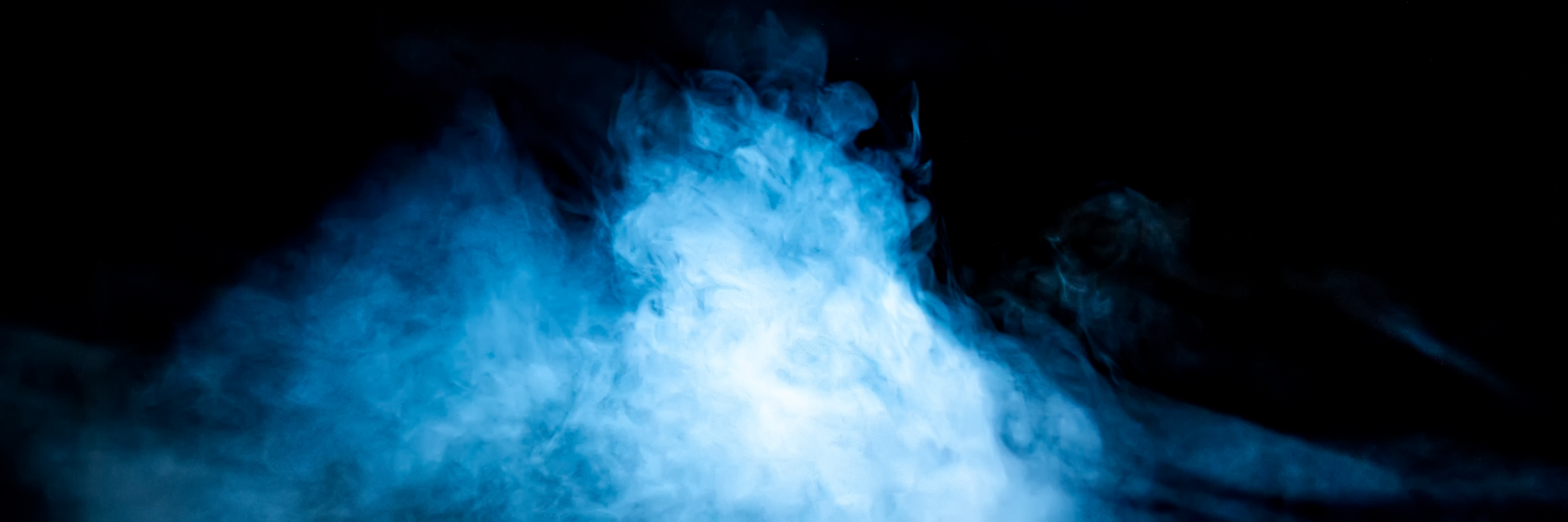 Stage haze illuminated in blue light against a black backdrop