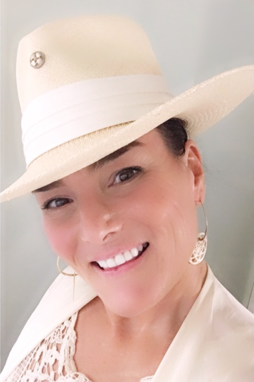 A woman wearing a white hat and smiling.