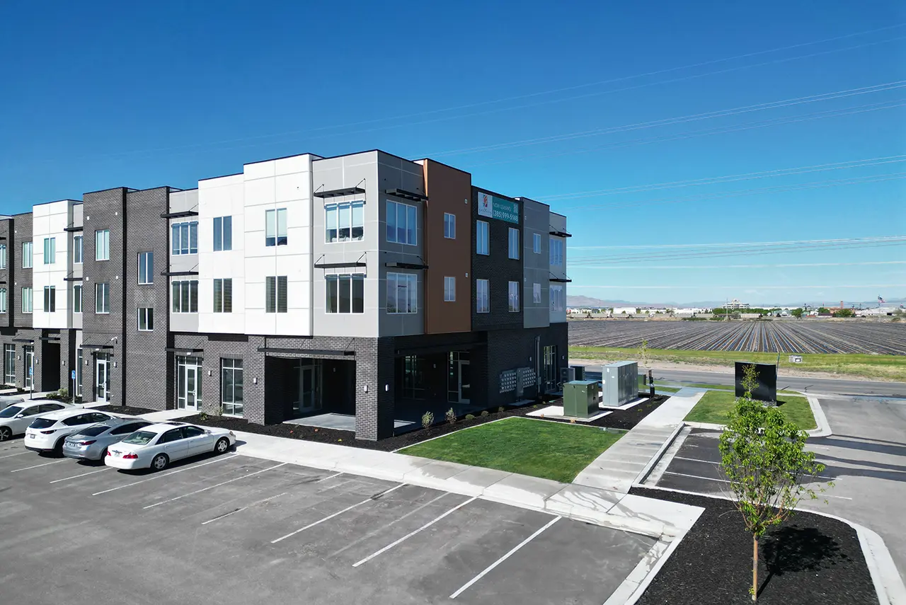 Exterior view of Gallery Apartments with modern design, open parking, and surrounding Springville landscape.