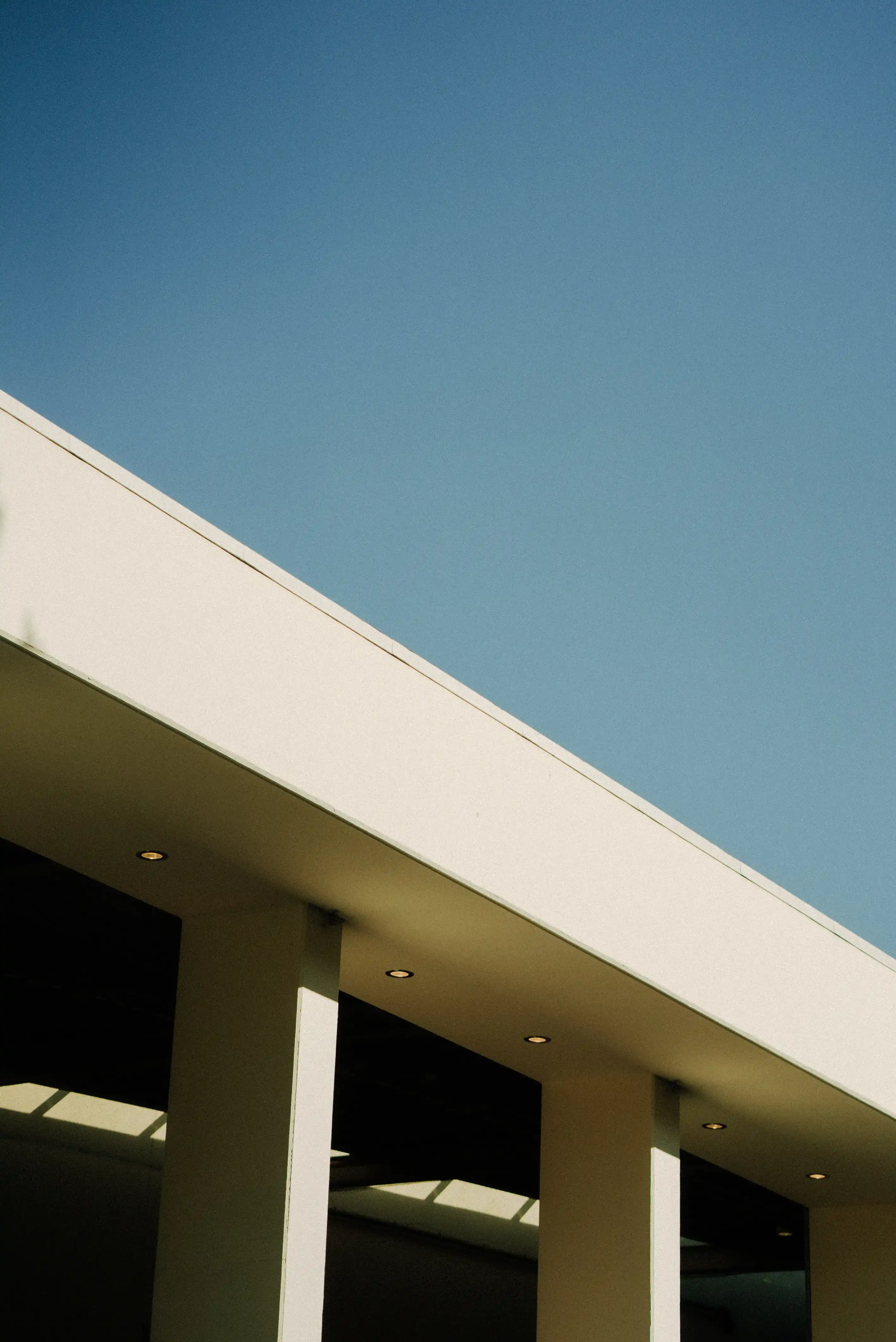 Modern building facade with white pillars and a clear blue sky.