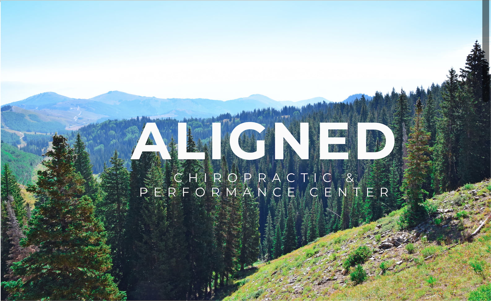 Mountain landscape with dense evergreen forest and text overlay saying 'ALIGNED Chiropractic & Performance Center'.