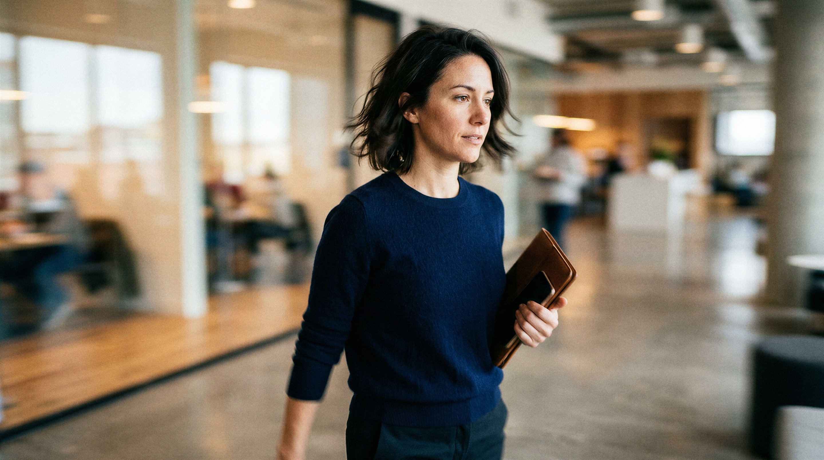 Woman walking through a modern office holding a tablet