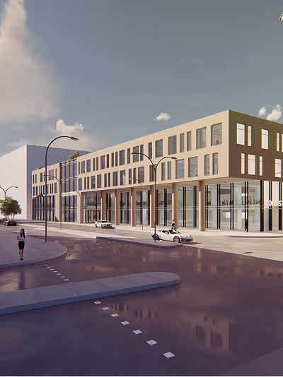 Modern multi-story building with large glass windows along a city street, under a partly cloudy sky.