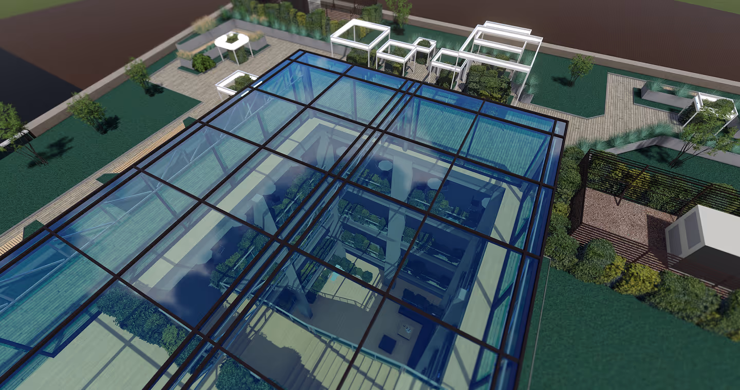 Top-down view of a modern glass-roofed building with visible interior courtyard and surrounding landscaped garden with benches and pathways.