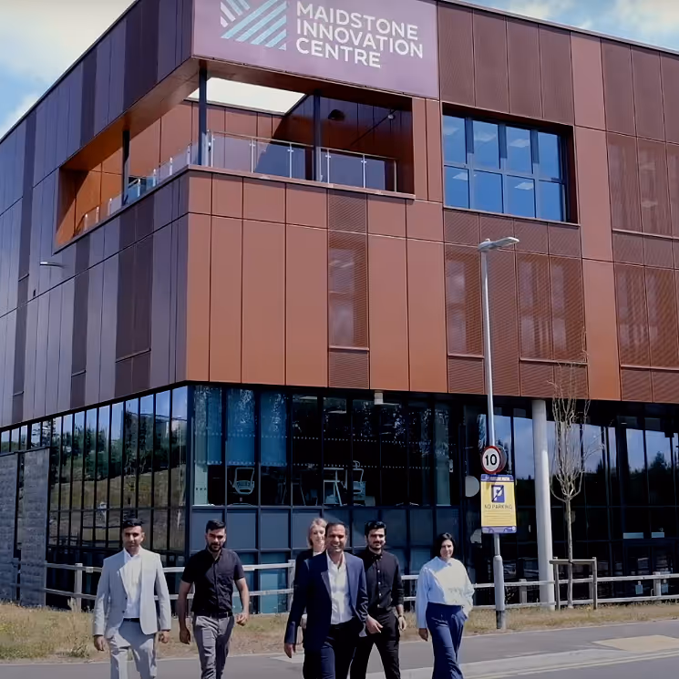 Group of six professionals walking outside a modern building with a sign reading Maidstone Innovation Centre.