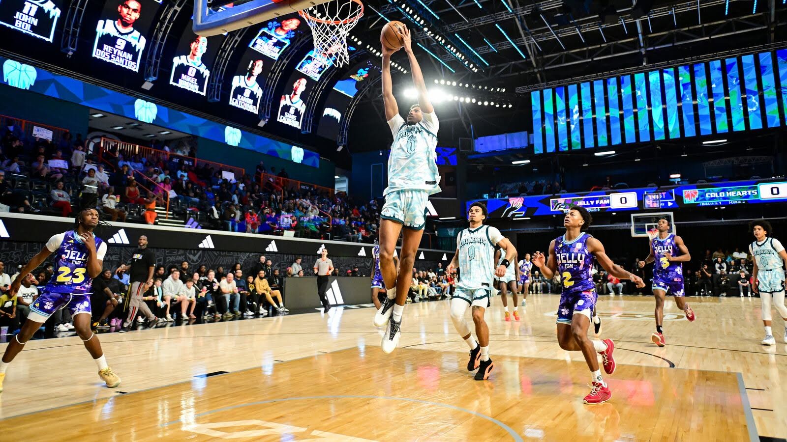 Basketball player in white jersey jumping to make a shot while opponents in purple jerseys defend on a crowded indoor court.