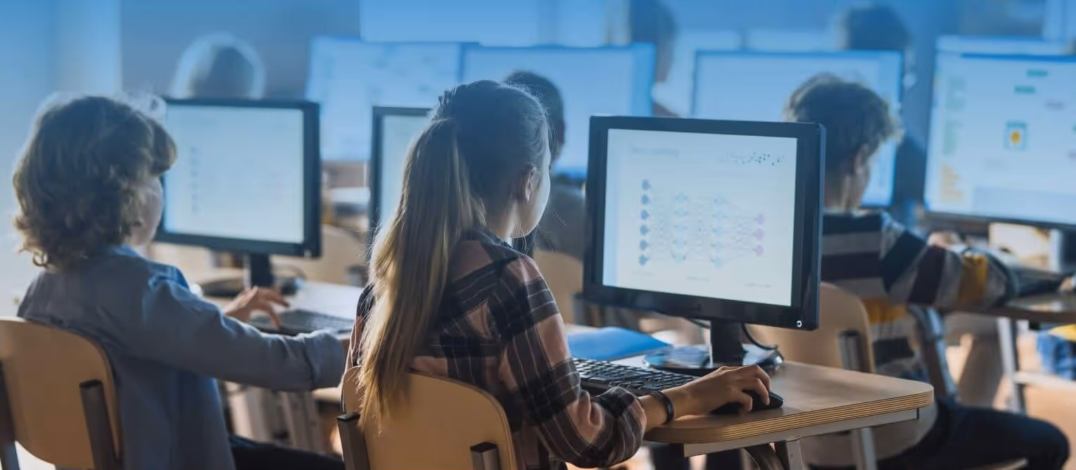 Children sitting at desks working on desktop computers in a classroom.