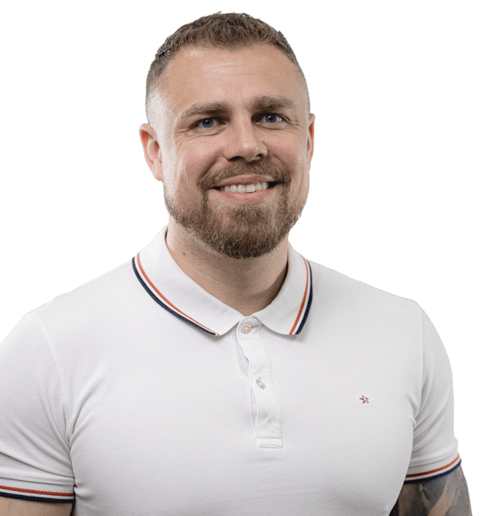 Usmívající se muž s krátkými vlasy, plnovousem a bílým polokošilovým tričkem s červenými a modrými proužky na límci a rukávech.