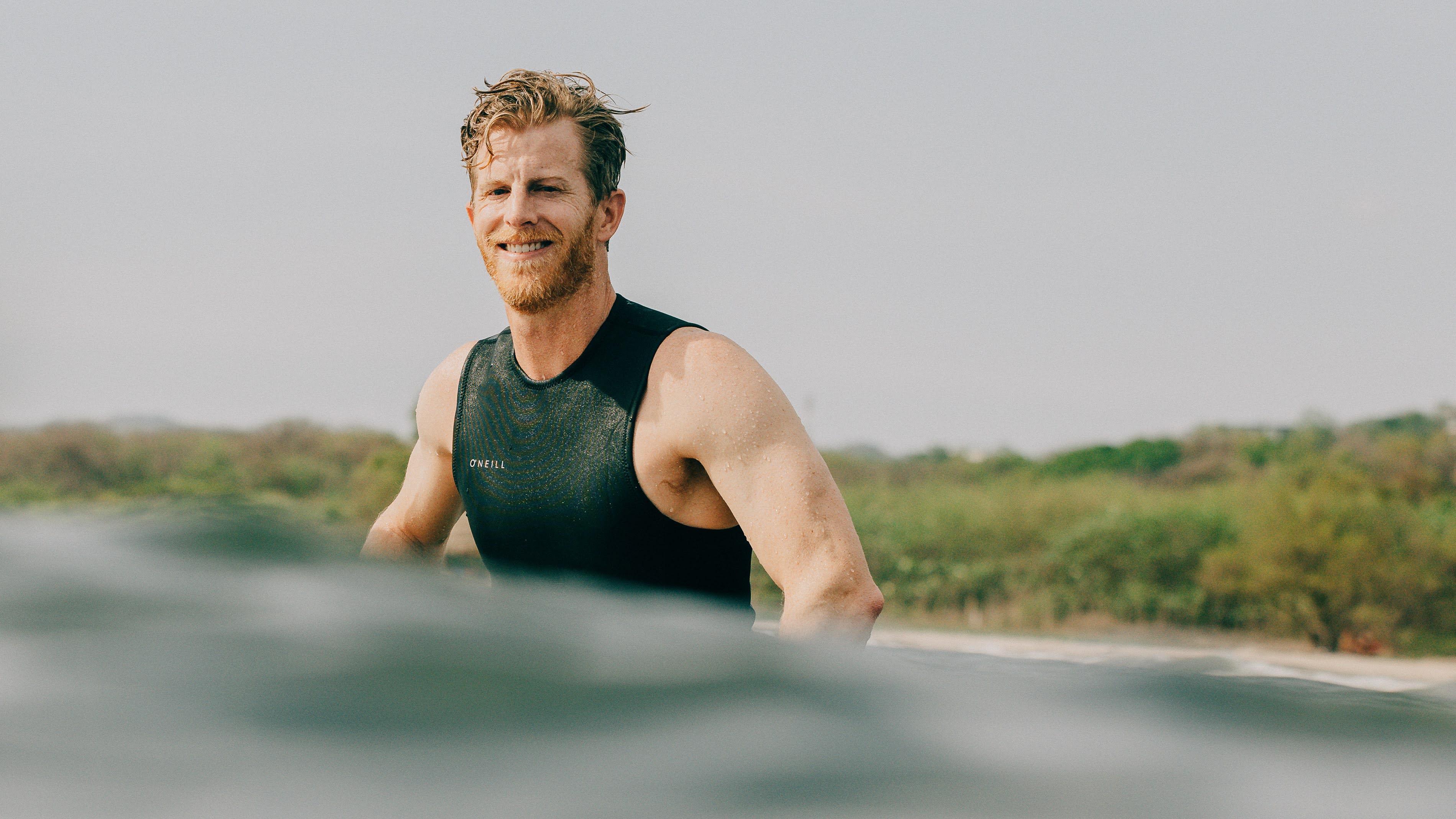 a photo of boulder colorado photographer cody strate sitting on a surf board in the ocean in Nosara Costa Rica at Surf Simply Resort