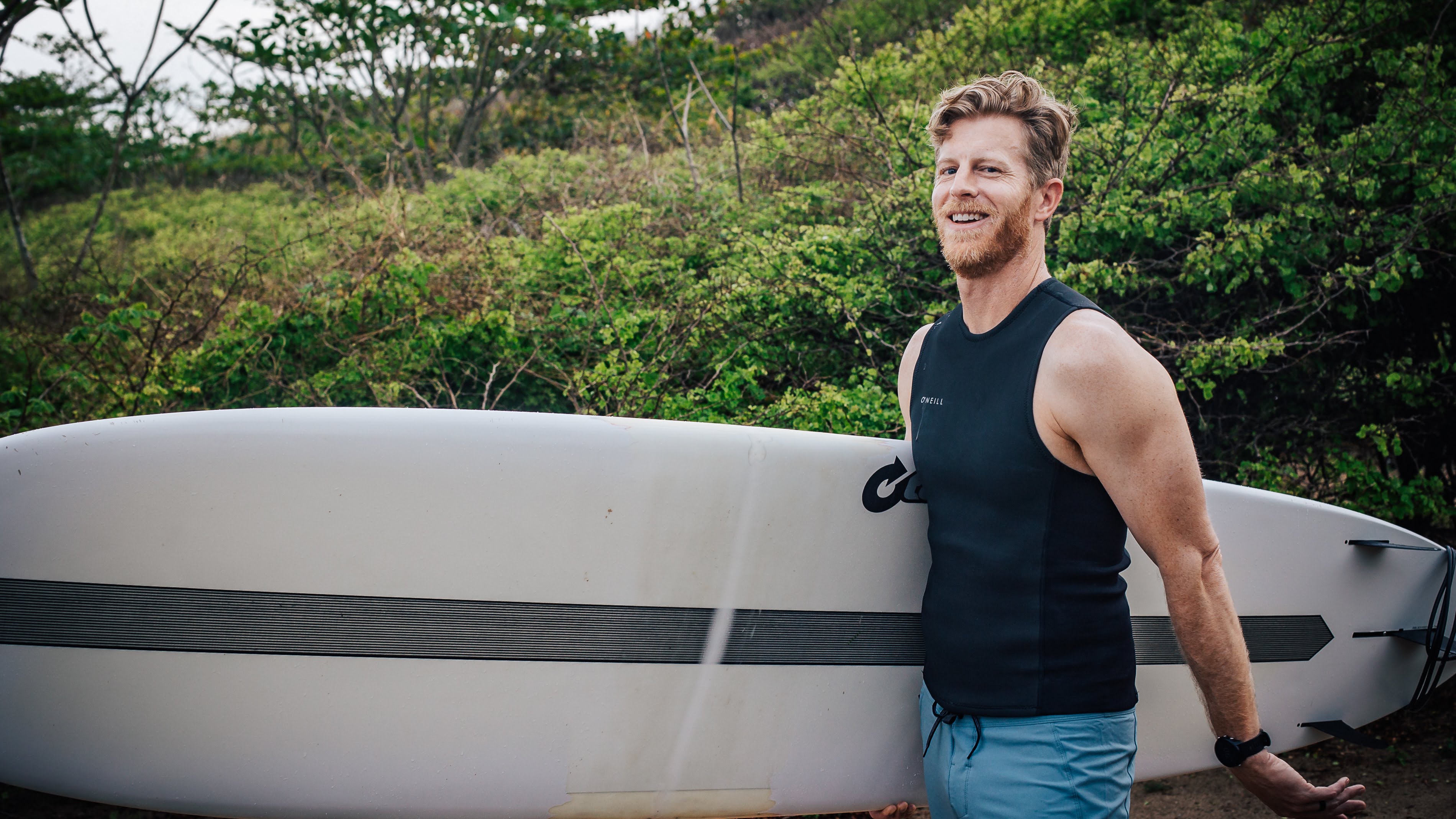 A portrait of Cody Strate holding a surfboard in Costa Rica at Surf Simply Resort