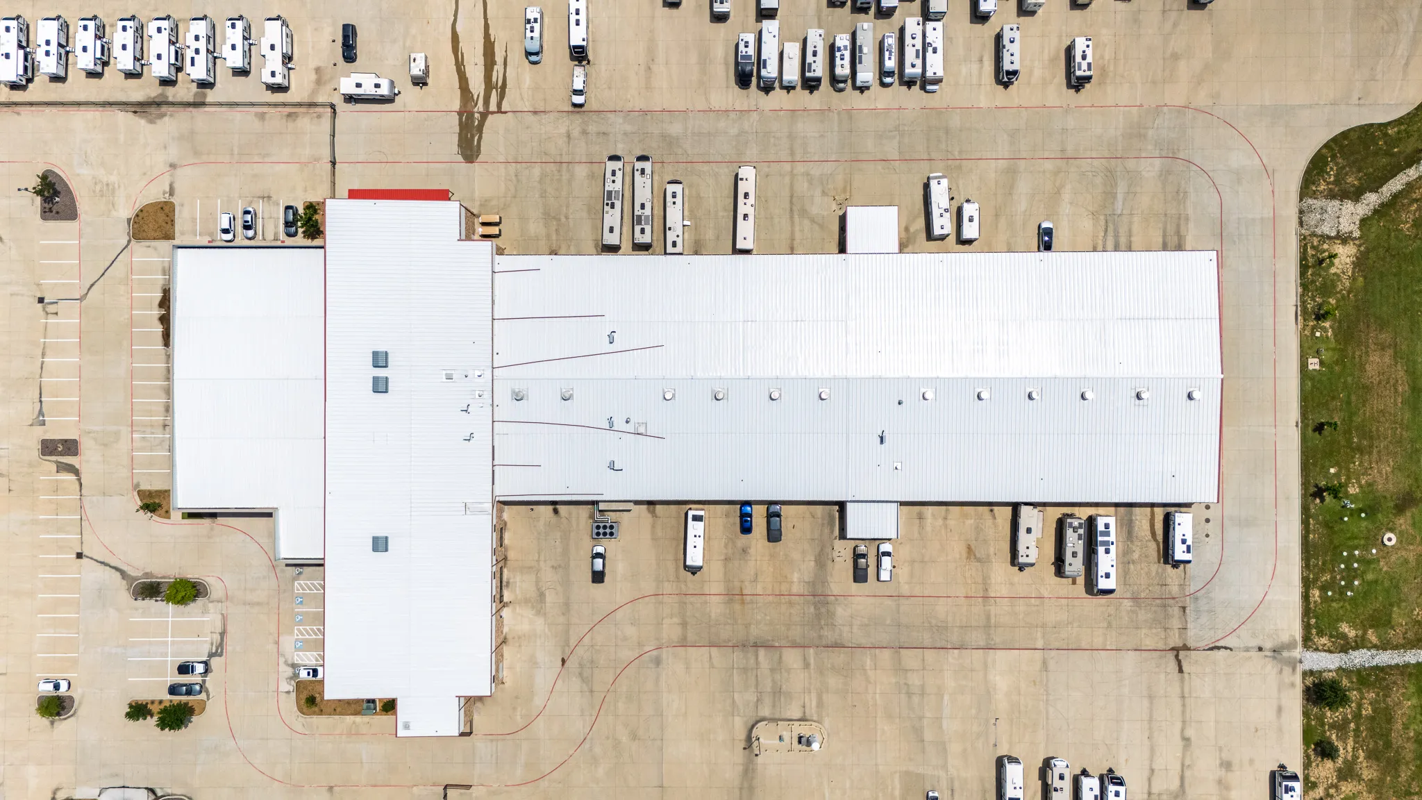 Aerial view of a large industrial building with a white roof, surrounded by parking lots and numerous recreational vehicles parked nearby taken by boulder colorado photographer Cody Strate