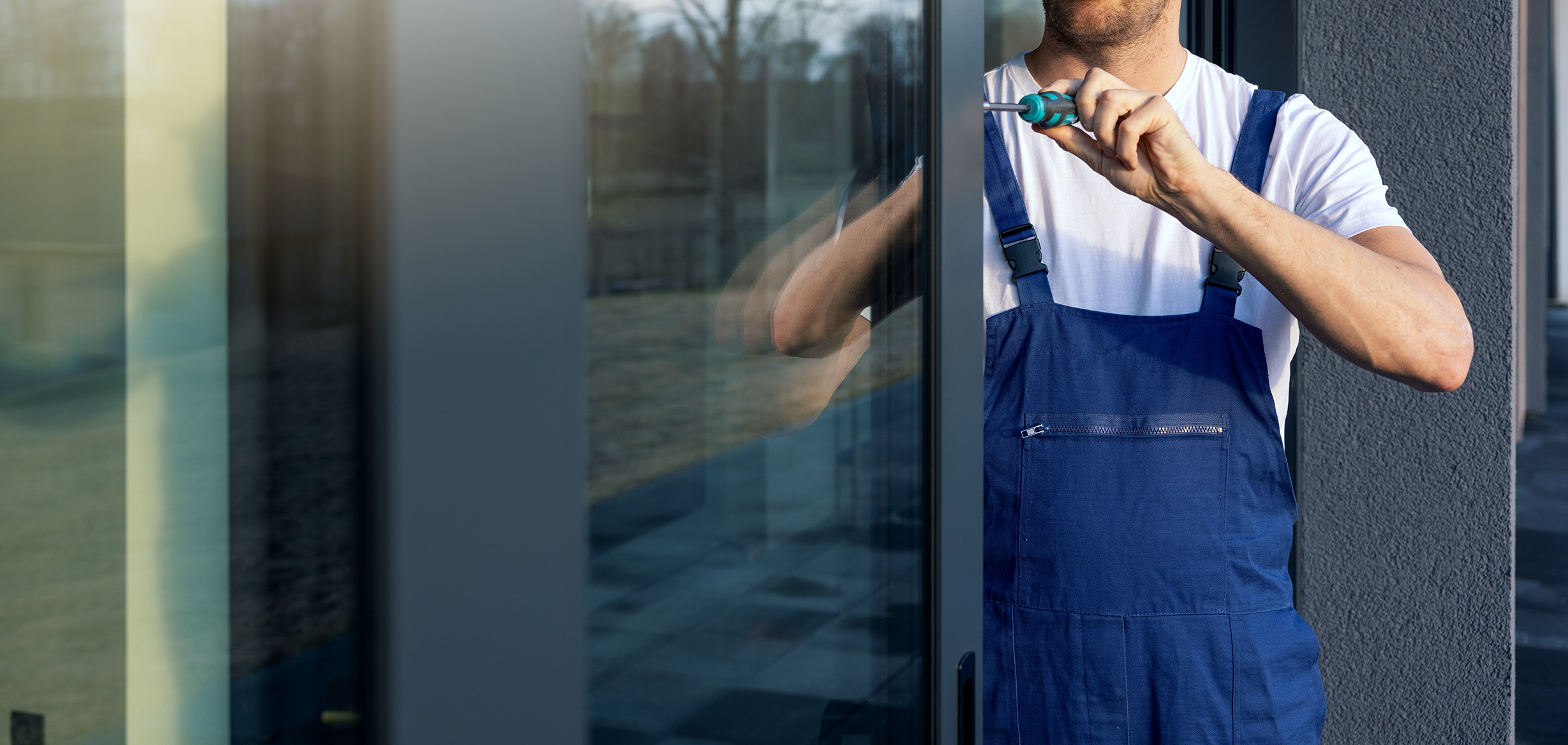 A man fixing a sliding door with a. screwdriver