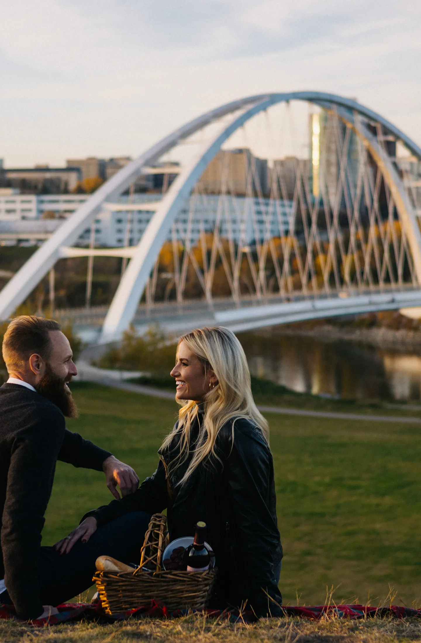 couple having a picnic in edmonton with the bridge and downtown in the background