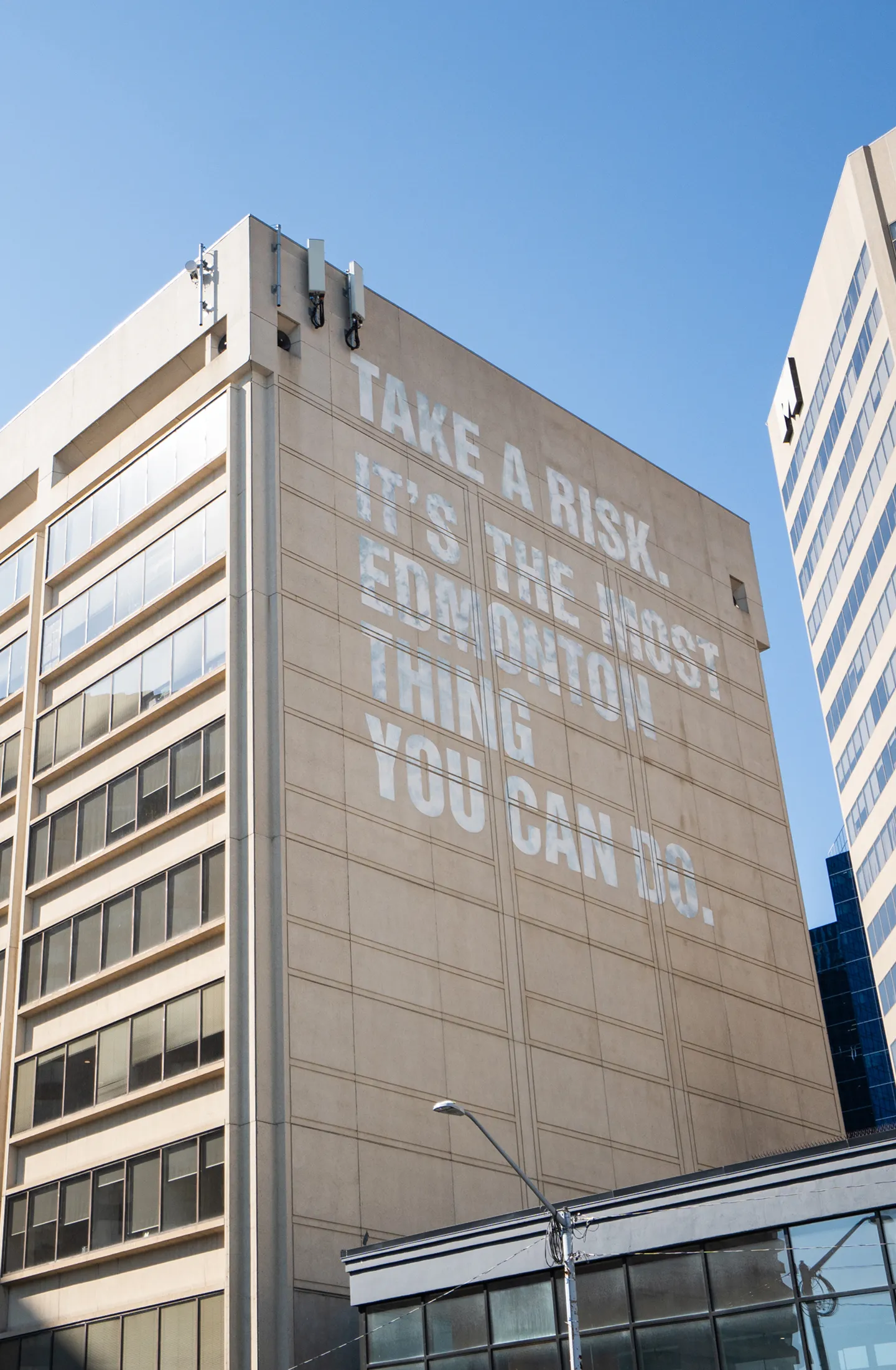 Downtown Edmonton building with writing on site reading take a risk its the edmonton thing to do