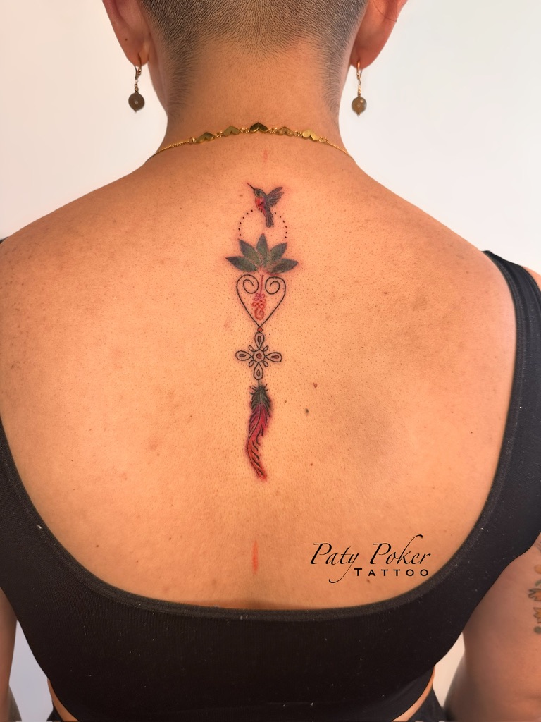 Back tattoo with a small hummingbird, heart-shaped design, and a feather extending downward.