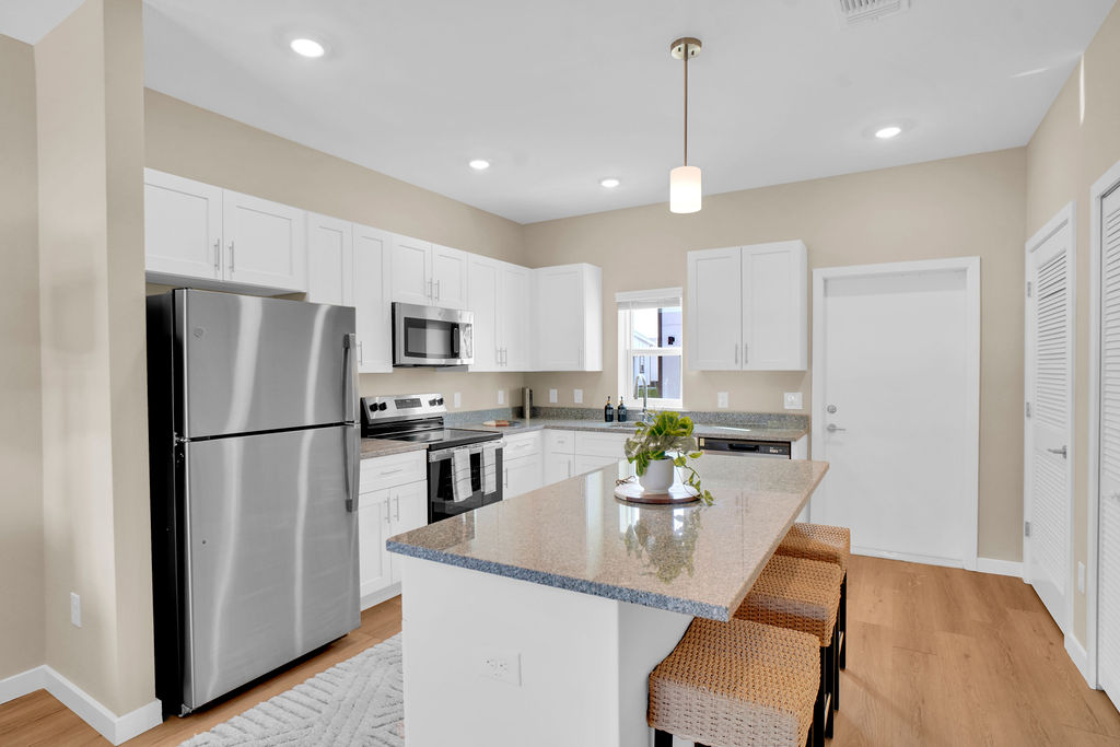 Kitchen with island and chairs, stainless steel appliances and white cabinets