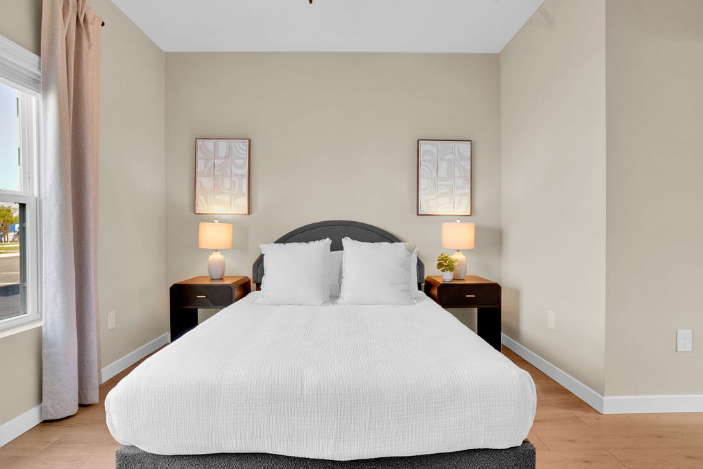 Bedroom with bed, bedside tables with lamps, and wall art