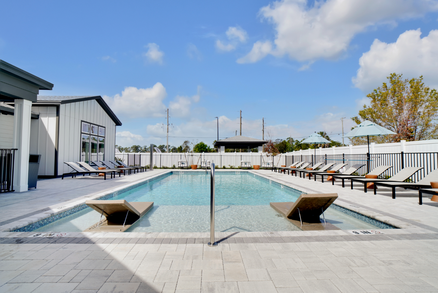 Swimming Pool featuring lounge chairs with umbrellas and view of clubhouse exterior