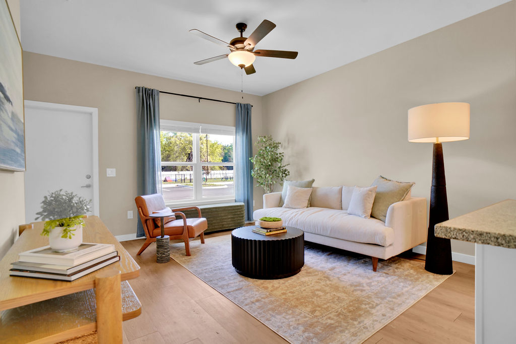 Living room with couch, ceiling fan, coffee table, lamp, chair, and window with curtains